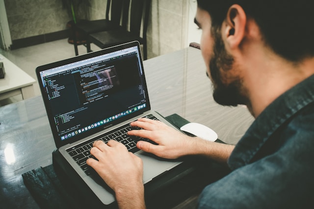 An employee coding AI and machine learning scripts on a laptop.